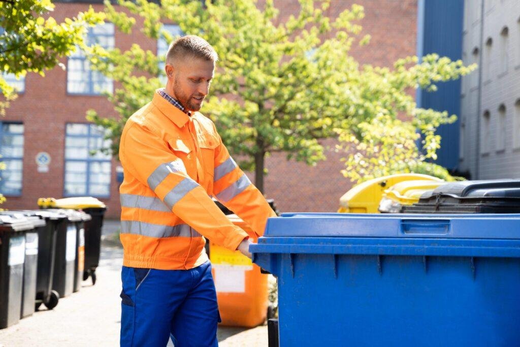 Industrial skip bin hire Geelong — worker in hi-vis vest beside a hook bin at an industrial facility serviced by Geelong All Bins